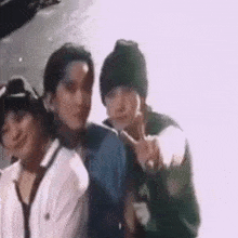 a group of young men are standing next to each other and giving peace signs .