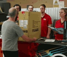 a man in a grey shirt is holding a cardboard box that says ' product name ' on it