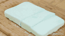 a knife is cutting a piece of marshmallow on a cutting board that says made in animonica