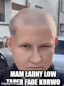 a man with a shaved head is making a funny face while standing in front of a building .