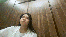 a woman is sitting in front of a wooden wall looking at the camera .