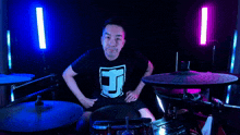 a man in a black shirt with the letter j on it is playing drums
