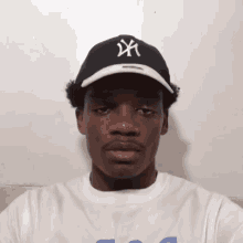 a young man wearing a black ny hat and a white shirt