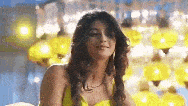 a woman in a yellow dress is sitting in front of a row of yellow lamps .