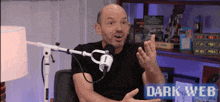 a man is sitting in front of a microphone with the words dark web on the bottom right