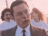 a man in a suit and tie stands in front of a crowd of people