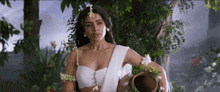 a woman in a white crop top holds a pot of water