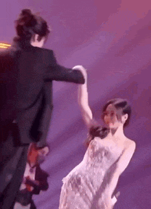 a man and a woman are dancing on a stage . the woman is wearing a white dress .