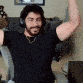 a man with a beard wearing headphones and a black shirt is flexing his muscles