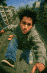a young man in a gray sweatshirt is jumping in the air