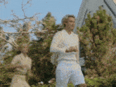 a man in a white sweater and white shorts stands in front of a house