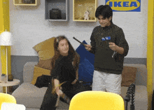 a man and a woman are playing in front of a ikea sign
