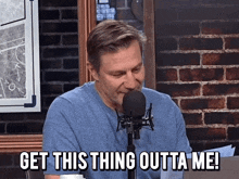 a man sitting in front of a microphone with the words get this thing outta me