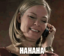 a woman is laughing while talking on a cell phone and the word hahaha is on her face .