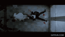 a man in a suit is laying on the floor with a gifrun.com watermark