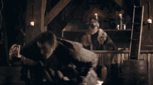 a man holding a sword in a dark room with candles in the background