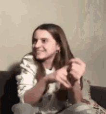 a woman is sitting on a couch with her hands folded .