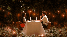 a man and a woman are sitting at a table with candles on it