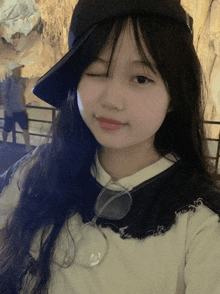a girl wearing a hat and glasses winks for the camera