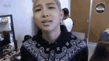a close up of a person 's face in a room with a mirror and a sign that says bts bomb .