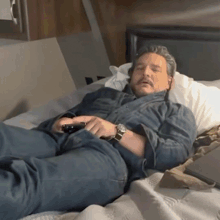 a man laying on a bed with his eyes closed holding a remote control