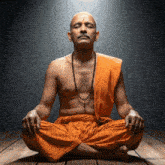 a man in an orange robe is meditating with his eyes closed