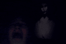 a man is screaming in the dark while a ghost is standing behind him .