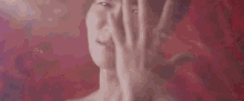 a close up of a woman covering her face with her hands .