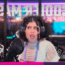 a woman wearing headphones stands in front of a microphone in front of a sign that says " game "