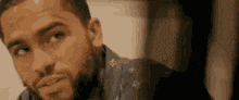 a close up of a man 's face with a beard looking at something .