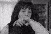 a black and white photo of a woman with her hand on her face .