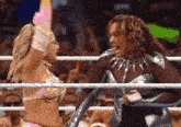 two women are wrestling in a wrestling ring and one of them is holding another woman 's hand .