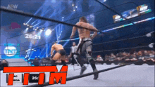 two men are wrestling in a wrestling ring with a referee watching .