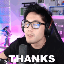 a man wearing glasses and headphones says thanks in front of a microphone