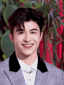 a young man wearing a plaid suit and white shirt smiles