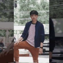 a young man wearing a striped shirt and a blue jacket is kneeling down