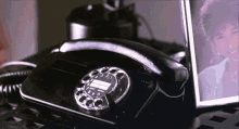 a black telephone sitting on a table next to a picture