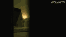 a woman is peeking out of a bathtub in a dark room with a candle .