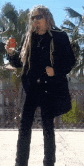 a man with dreadlocks and sunglasses holds a can of soda