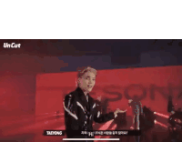 a man in a black jacket is standing on a stage in front of a crowd .