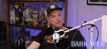 a man is sitting in front of a microphone wearing a black shirt that says budweiser on it .
