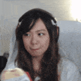 a young woman wearing headphones is sitting in a chair holding a stuffed animal .
