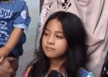 a young girl is talking into a microphone while standing next to a woman and child .