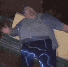 a man in a blue lightning suit is dancing in a dark room .