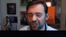 a man with his eyes closed looks at the camera with a lamp in the background