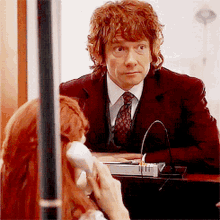 a man in a suit and tie is talking on a cell phone