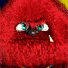 a close up of a red stuffed animal with green eyes and a purple mouth .