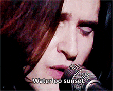 a woman singing into a microphone with the words waterloo sunset written below her