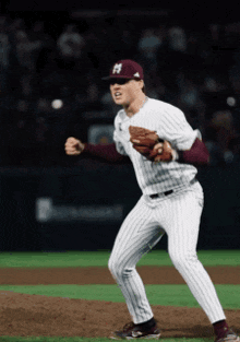 a baseball player wearing a maroon and white uniform with the letter h on his hat