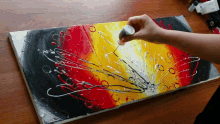 a person is painting on a canvas with a brush and a bottle of acrylic paint in the background